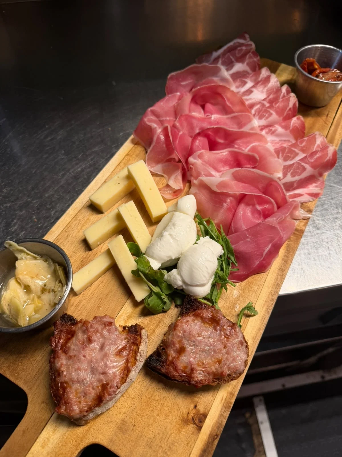 Klassische Platte von Putea mit Wurstwaren, Käse, Mozzarellaknoten und gerösteten Brotscheiben